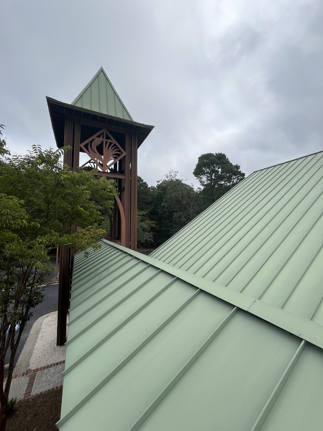 Well-maintained institutional property with a clean sage-green metal roof and bell tower