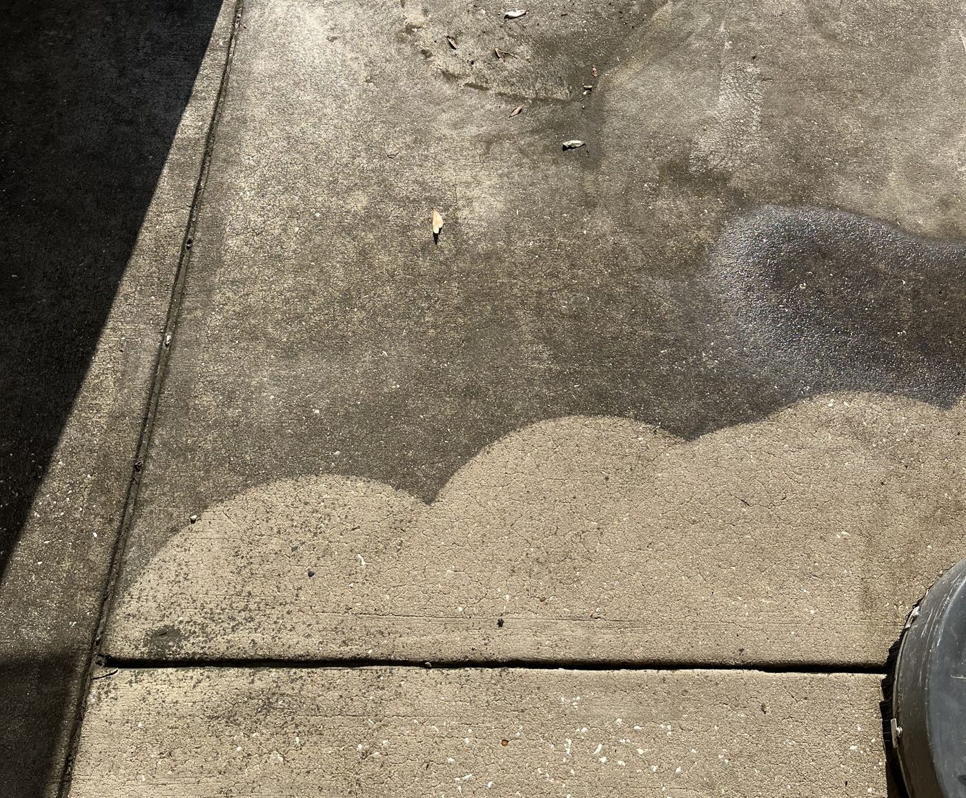Concrete mid-clean — bright washed arcs against untouched gray
