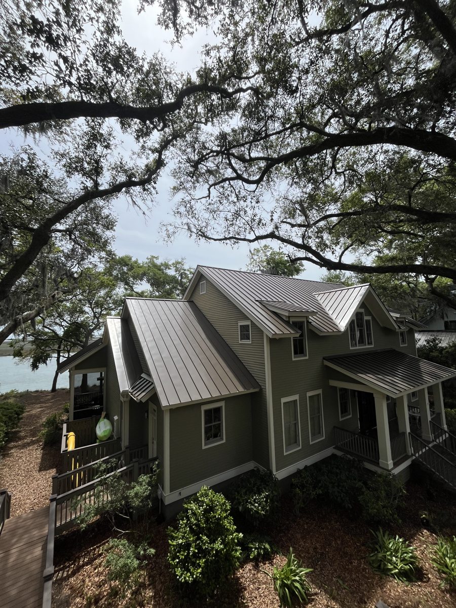 Coastal home with a freshly washed bronze metal roof under live oaks