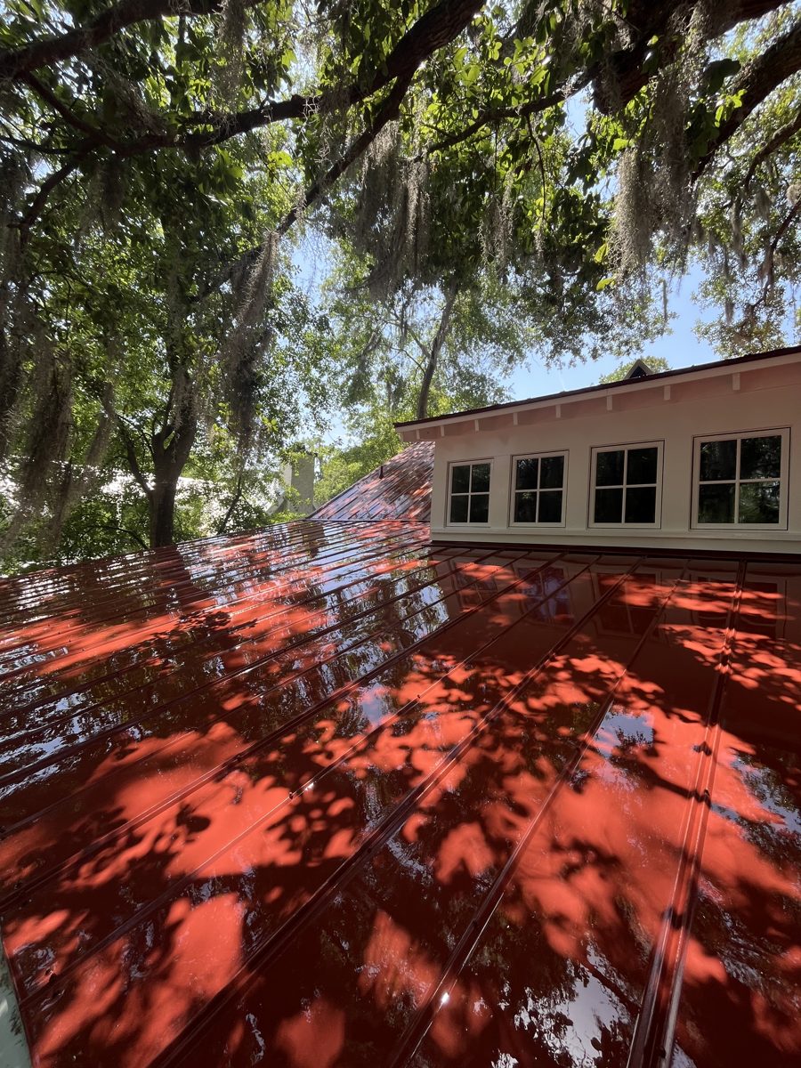 Glossy red metal roof beneath moss-draped live oaks