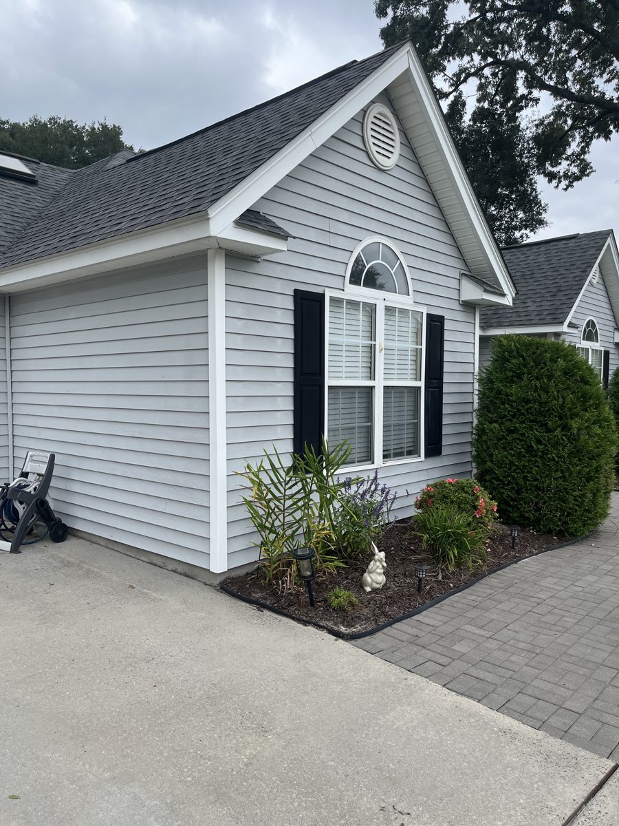 Clean white siding and paver walkway after a full exterior wash