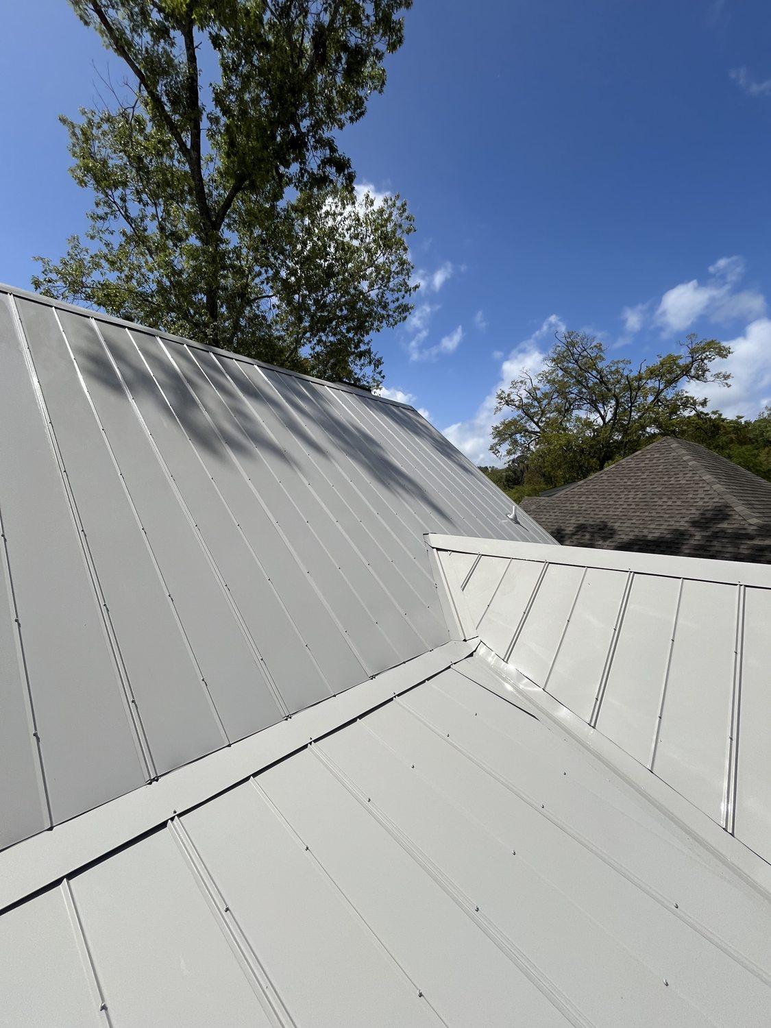 Bright white standing-seam metal roof, freshly soft-washed, against a clear blue sky